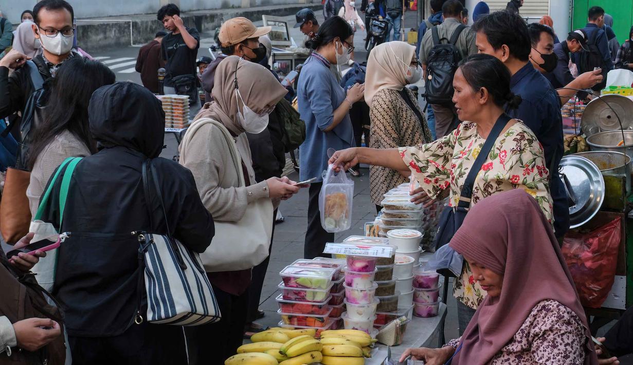 Para penjual makanan (kanan) menyiapkan pesanan pelanggan di salah satu warung makan saat jam sibuk di Jakarta pada Kamis 21 Mei 2026. (BAY ISMOYO/AFP)