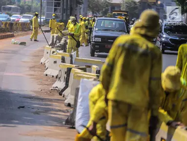 Petugas Dinas Bina Marga DKI Jakarta memperbaiki separator busway di kawasan Jalan Gatot Subroto, Jakarta, Selasa (1/10/2019). Separator busway dirusak massa saat terjadi bentrok antara polisi dengan demonstran di kawasan tersebut. (Liputan6.com/Faizal Fanani)