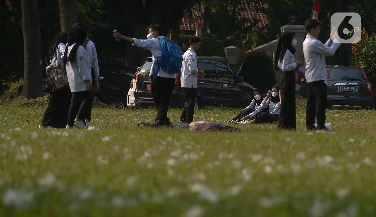Mahasiswa berfoto di rumput yang bercampur dengan kapas di halaman Institut Pertanian Bogor, Kota Bogor, Jawa Barat, Kamis (25/8/2022). Kapas yang berasal dari pohon kapuk randu yang sedang berguguran itu menjadi daya tarik bagi warga untuk berswafoto. (Liputan6.com/Angga Yuniar)