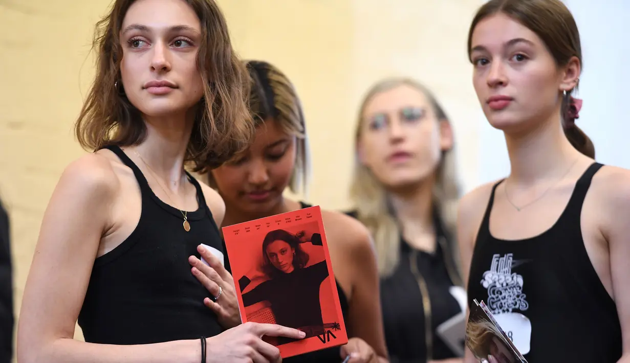 model memegang foto dirinya ketika menunggu casting untuk Melbourne Fashion Week, Australia (24/7/2019). Lebih dari 400 model tampil di Melbourne Meat Market yang ikonik menjadi salah satu dari 120-150 model yang dipilih untuk mode tersebut. (AFP Photo/William West)
