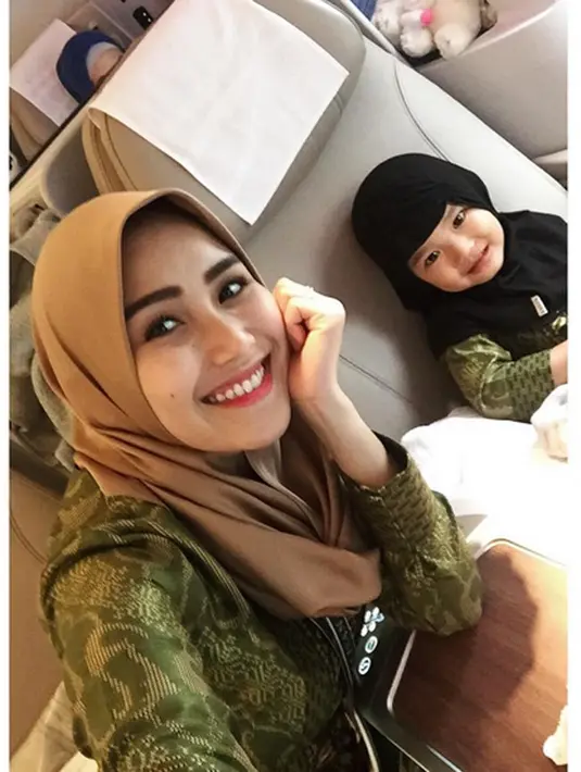 "Bismillah doakan bunda dan bilqis dan keluarga semuanya 🙏🏻🕋❤️" tulis Ayu Ting Ting dalam keterangan foto dirinya bersama buah hatinya, Bilqis Khumairah Razak saat di pesawat. (Instagram/ayutingting92)