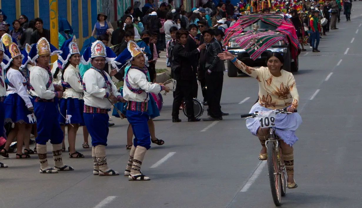 Seorang wanita melambaikan tangan saat mengikuti balapan sepeda Cholita di El Alto, La Paz, Bolivia (12/11). Dalam balapan sepeda ini peserta mengenakan topi bundar, rok dan selendang sulaman. (AP Photo / Juan Karita)