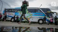 Peserta Mudik Aman Mudik Sehat Kementerian Perhubungan memanggul barang bawaan berjalan menuju bus tujuan kampung halamannya di Terminal Jatijajar, Depok, Jawa Barat, Kamis (28/4/2022). Sekitar 3.000 penumpang diberangkatkan dengan 106 bus yang telah disiapkan oleh Dirjen Darat Kementerian Perhubungan. (Liputan6.com/Faizal Fanani)