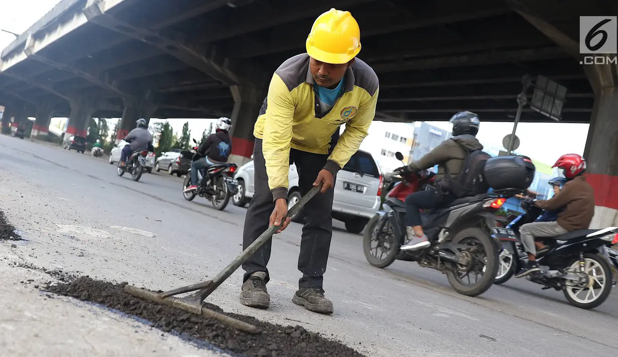 Petugas menambal lubang pada jalan yang rusak di kawasan Jatinegara, Jakarta, Kamis (7/2). Musim hujan yang mengguyur Jakarta selama beberapa waktu terakhir meninggalkan kerusakan pada sejumlah ruas jalan di Ibukota. (Liputan6.com/Immanuel Antonius)