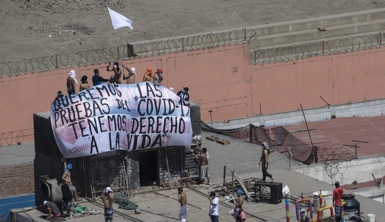 Narapidana membentangkan spanduk bertulis "Kami ingin tes COVID-19, kami memiliki hak untuk hidup” saat protes di Penjara Lurigancho, Lima, Peru, Selasa (28/4/2020). Narapidana mengeluhkan pihak berwenang tidak berbuat cukup untuk mencegah penyebaran COVID-19 dalam penjara. (AP Photo/Rodrigo Abd)