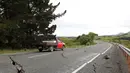 Sebuah truk melintasi jalan retak di dekat Kota Ward, selatan Blenheim, di bagian selatan Pulau Selandia Baru, Senin (14/11). Gempa 7,8 SR yang mengguncang Selandia Baru mengakibatkan jalan tersebut retak. (REUTERS/Anthony Phelps)