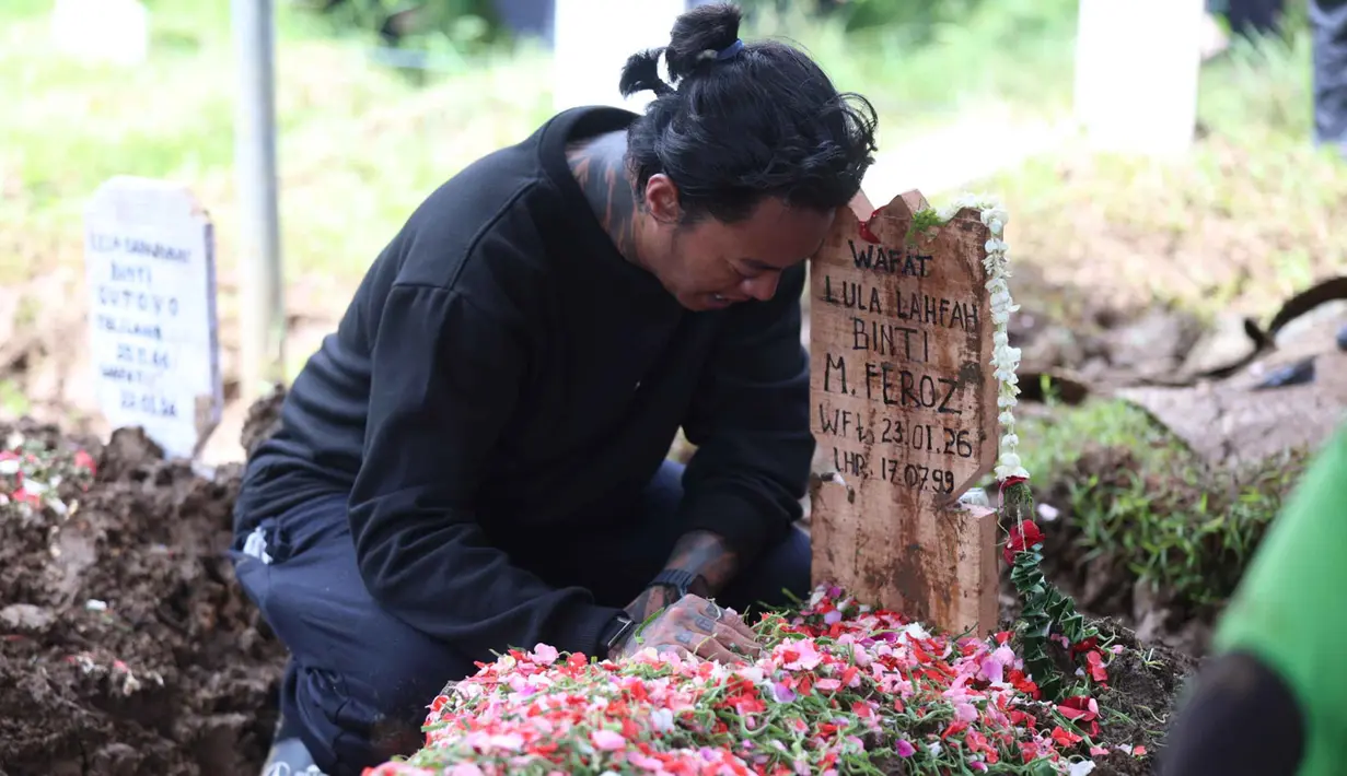 Konten kreator yang juga musisi, Reza Oktovian atau lebih dikenal dengan panggilan Reza Arap tertunduk di sisi nisan kekasihnya, Lula Lahfah, di Tempat Pemakaman Umum (TPU) Rawa Terate, Cakung, Jakarta Timur, pada Sabtu (24/1/2026). Selebgram Lula Lahfah dimakamkan di Tempat Pemakaman Umum (TPU) Rawa Terate, Cakung, Jakarta Timur, pada Sabtu (24/1/2026). (Kapanlagi.com/Budy Santoso)