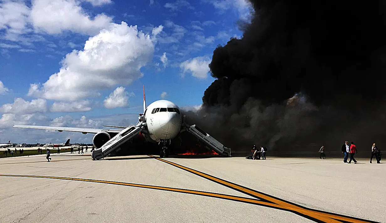 Penumpang dievakuasi dari pesawat Boeing 767-200ER milik maskapai Dynamic International Airways yang terbakar saat akan lepas landas di Bandara Fort Lauderdale, Florida, Kamis (29/10). 15 orang terluka akibat kejadian tersebut. (AFP PHOTO/Andres Gallego)