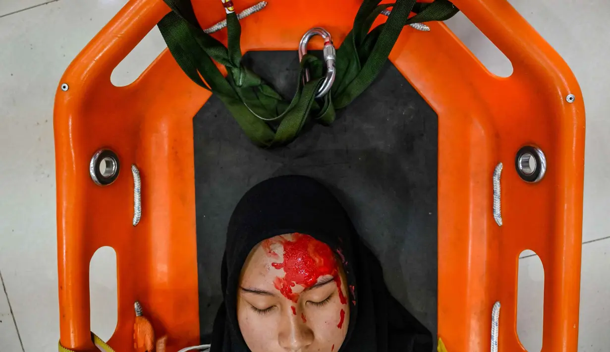 Simulasi ini melibatkan beberapa skenario evakuasi dari ketinggian, yang mencakup prosedur menyelamatkan korban luka dengan cara diturunkan secara aman menggunakan peralatan khusus. (CHAIDEER MAHYUDDIN/AFP)
