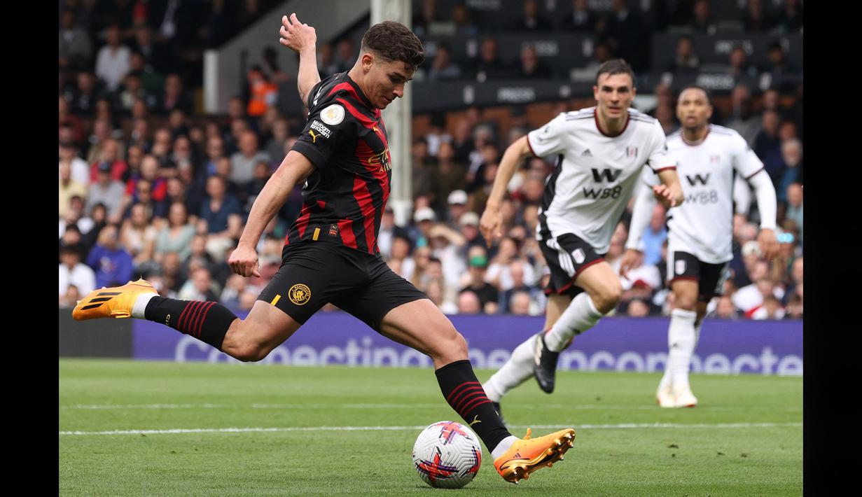 Pemain Manchester City, Julian Alvarez (kiri), menendang bola ke gawang Fulham dalam pertandingan pekan ke-34 Premier League 2022/2023 yang berlangsung di Craven Cottage, Minggu (30/4/2023). Julian Alvarez yang menjadi partner Haaland di lini depan Manc City juga mencetak satu gol dalam pertandingan ini. (AFP/Adrian Dennis)