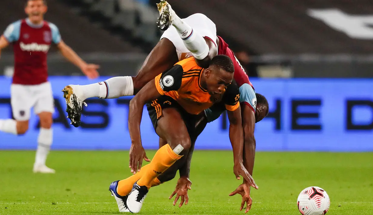 Gelandang West Ham, Michail Antonio jatuh di atas pemain Wolverhampton Wanderers Willy Boly dalam lanjutan Liga Inggris di London Stadium, Minggu (27/9/2020). West Ham United menang dengan skor telak 4–0 atas tamunya Wolverhampton Wanderers. (Frank Augstein/Pool via AP)