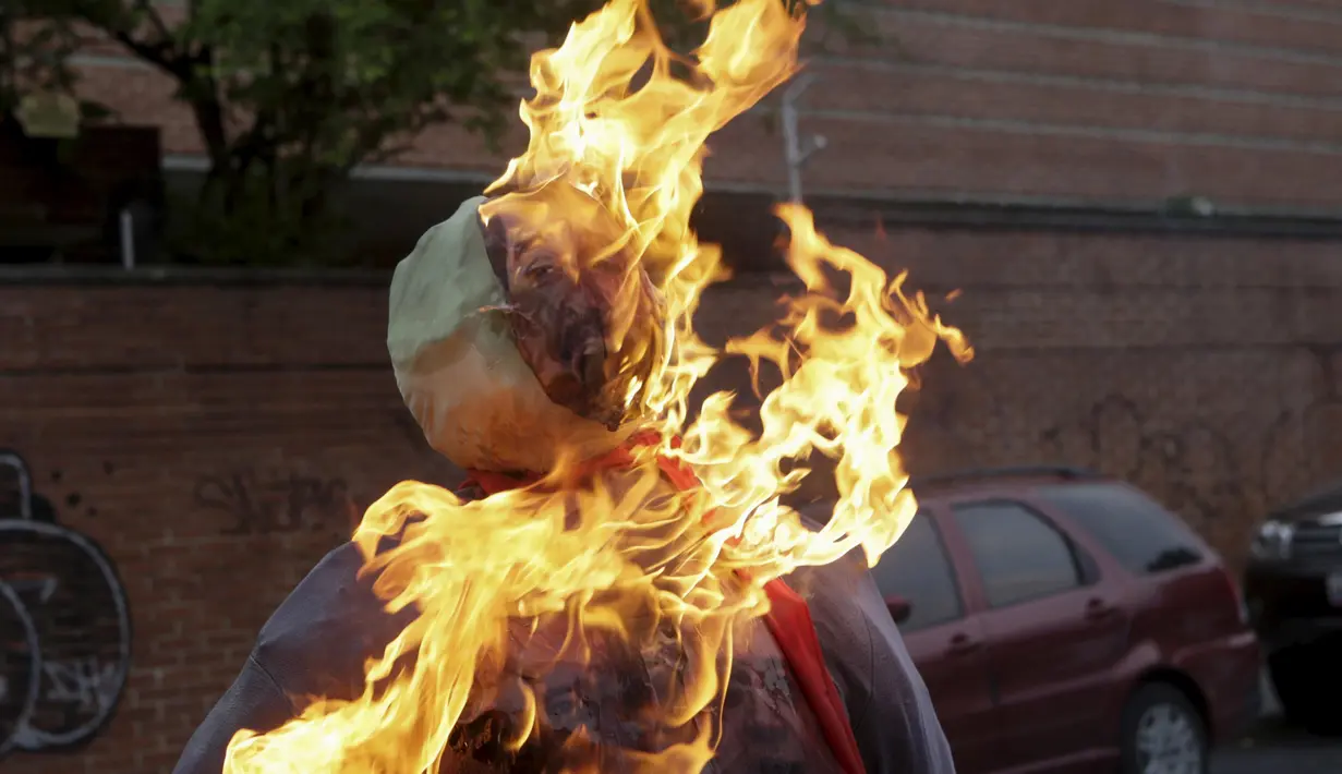 Patung bergambar Presiden Venezuela Nicolas Maduro dibakar oleh warga di Caracas , Venezuela, (27/3). Proses ini juga masuk dalam tradisi " Pembakaran Yudas " tetapi bedanya patung tersebut ditempel gambar Nicolas Maduro. (REUTERS / Marco Bello)