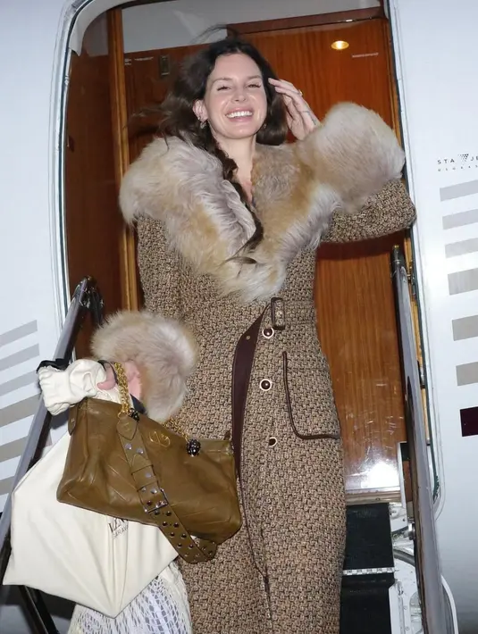 Lana Del Rey tampil serba coklat mengenakan coat berbulu serasi dengan tas Valentino Garavani Panthea yang menggabungkan dua jenis kulit nappa, yaitu matte dan waxed, yang dibentuk dalam pola chevron elegan.  [Dok. Valentino]