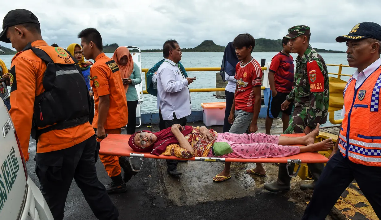 Anggota dari tim penyelamatan membawa seorang pengungsi lansia dengan tandu usai dievakuasi dari Pulau Sebesi di Pelabuhan Bakauheni, Lampung, Rabu (26/12). (AFP Photo/Mohd Rasfan)