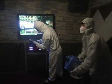 Petugas mengenakan pakaian pelindung menyemprotkan Disinfektan untuk mencegah penyebaran virus corona Covid-19 di Karaoke di Seoul, Korea Selatan, (13/3/2020). Penyemprotan disinfektan terus dilakukan di setiap sudut tempat di Korsel. Salah satunya sampai ke tempat karaoke. (AP Photo/Ahn Young-joon)