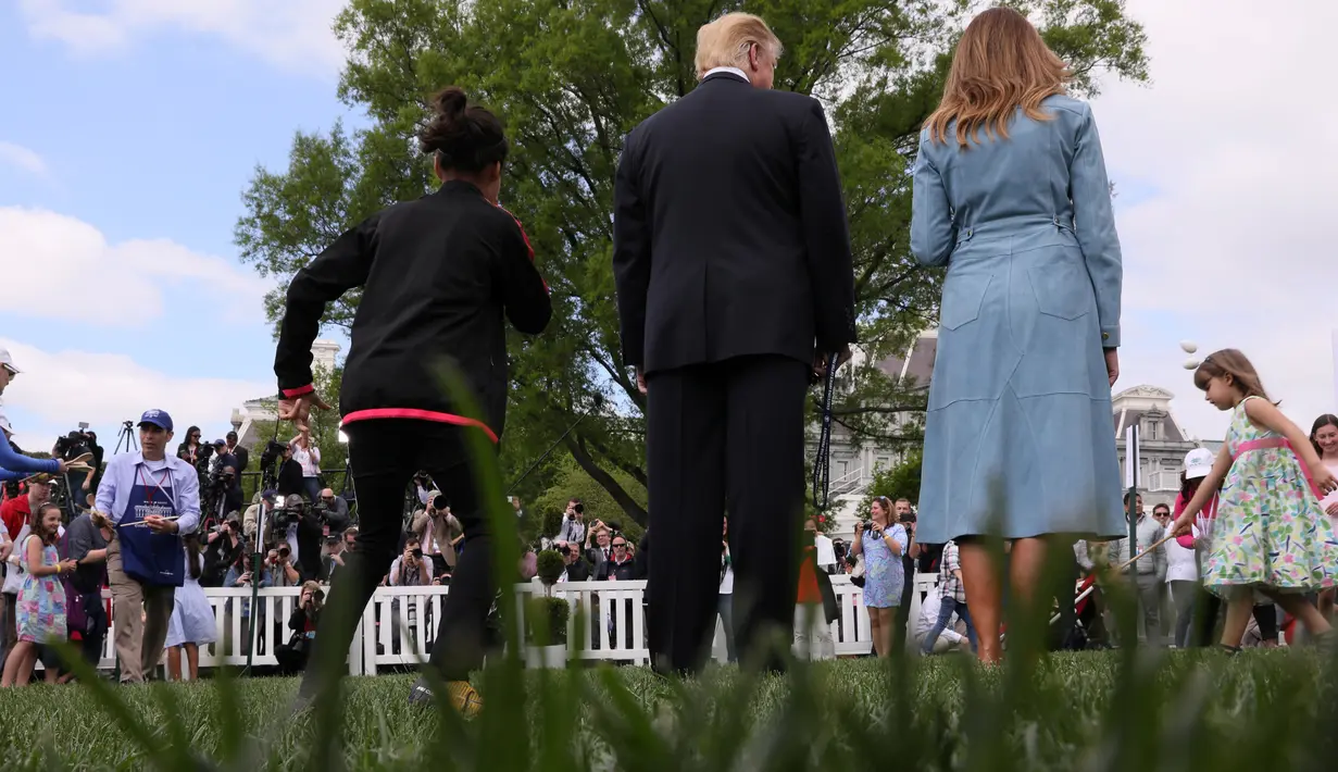 Presiden AS Donald Trump dan Ibu Negara Melania Trump menyaksikan anak-anak menggelindingkan telur paskah di South Lawn Gedung Putih, Washington, Senin (22/4). Acara tahunan itu merupakan bagian dari rangkaian memperingati Paskah yang rutin diselenggarakan Gedung Putih. (REUTERS/Jonathan Ernst)