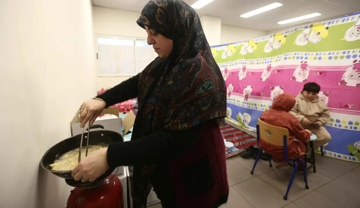 Lebih dari setengah juta warga terpaksa mengungsi setelah serangan Israel menghantam beberapa wilayah di Lebanon. Tampak dalam foto, seorang perempuan pengungsi yang tinggal bersama keluarganya di ruang kelas sekolah, setelah melarikan diri dari serangan udara Israel di pinggiran selatan Beirut, Lebanon, duduk untuk berbuka puasa bersama, pada 7 Maret 2026. (Ibrahim AMRO/AFP)