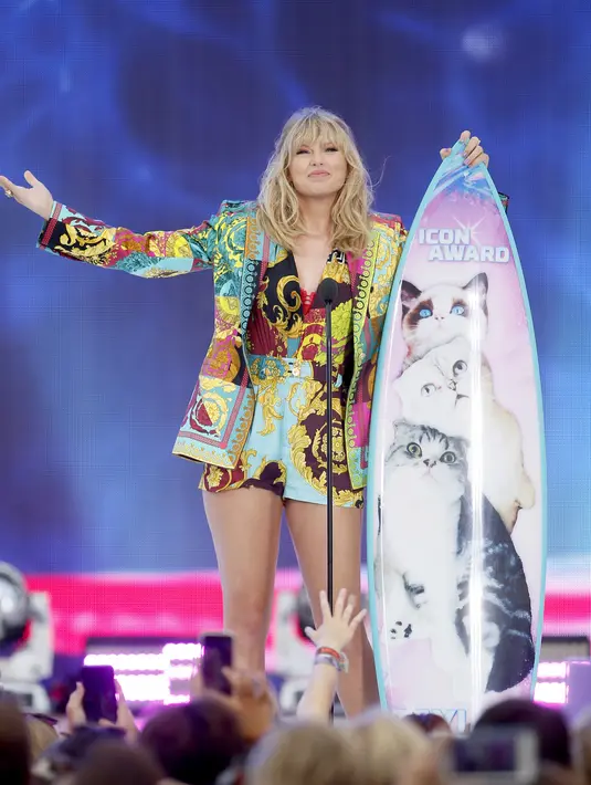 Ekspresi Taylor Swift saat menerima penghargaan Icon Award selama FOX's Teen Choice Awards 2019 di Hermosa Beach, California (11/8/2019). Penyanyi 29 tahun ini tampil cantik mengenakan busana keluaran Versace.  (AP Photo/Danny Moloshok)