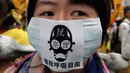 Seorang pengunjuk rasa mengenakan masker polusi anti-udara selama demonstrasi menuntut pemerintah Taiwan untuk pengurangan polusi udara di Taipei (26/12). Ratusan warga berbaris di jalan-jalan memprotes kebijakan energi pemerintah. (AFP PHOTO/Sam Yeh)