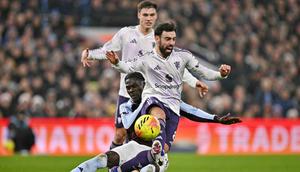 Gelandang Manchester United, Bruno Fernandes, dibekap cedera saat timnya kalah 1-2 dari Aston Villa pada laga pekan ke-17 Premier League di Villa Park, Minggu (21/12/2025) malam WIB. (AFP/Ben STANSALL)