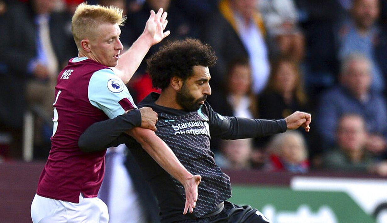 Penyerang Liverpool, Mohamed Salah, berebut bola dengan pemain Burnley, Ben Mee, pada laga Premier League 2019 di Stadion Turf Moor, Sabtu (31/8). Liverpool menang 3-0 atas Burnley. (AP/Anthony Devlin)