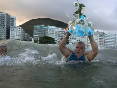 Penganut kepercayaan Afro-Brasil membawa persembahan untuk Dewi Laut, Yemanja dalam tradisi upacara menjelang tahun baru di pantai Copacabana, Rio de Janeiro, Sabtu (29/12). Mereka melarung sesaji sebagai bentuk syukur kepada dewi laut. (AP/Leo Correa)