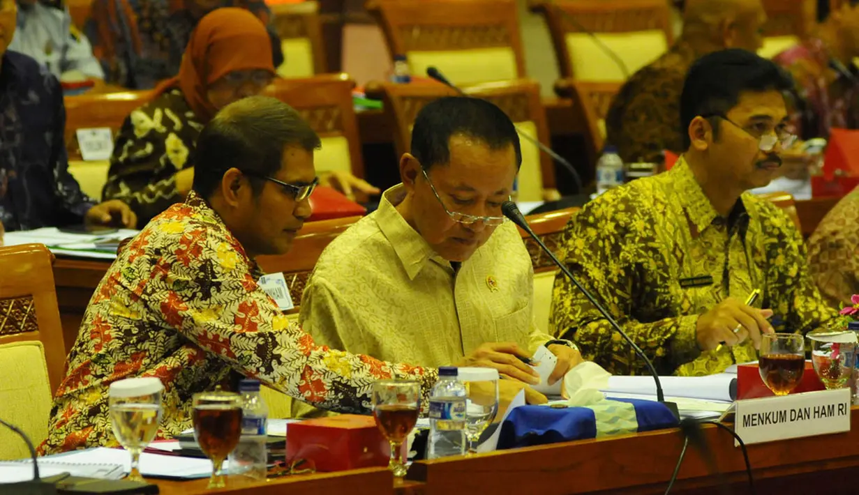 Menteri Hukum dan Hak Asasi Manusia, Amir Syamsuddin (tengah), berdiskusi dengan salah satu staffnya saat mengikuti rapat kerja dengan Komisi III DPR RI di Gedung Parlemen, (28/8/2014). (Liputan6.com/Andrian M Tunay)