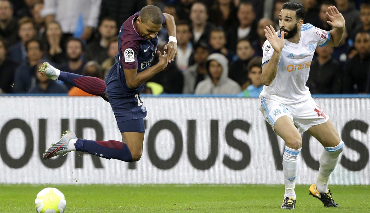 Pemain PSG, Kylian Mbappe (kiri) melompat saat diadang pemain Marseille, Adil Rami pada lanjutan Ligue 1 di  Velodrome Stadium, Marseille, (22/10/2017). PSG bermain imbang 2-2 melawan Marseille. (AP/Claude Paris)