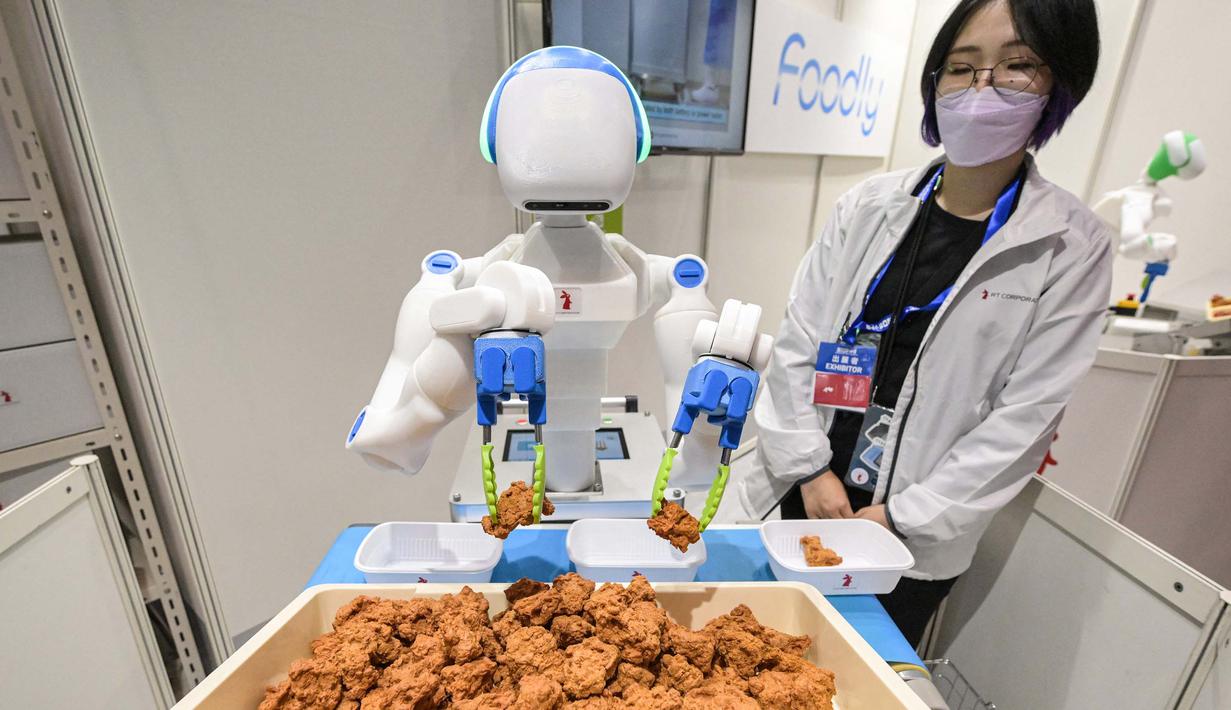Sebuah robot menyortir dan menempatkan potongan ayam goreng ke dalam wadah. (Richard A. Brooks/AFP)