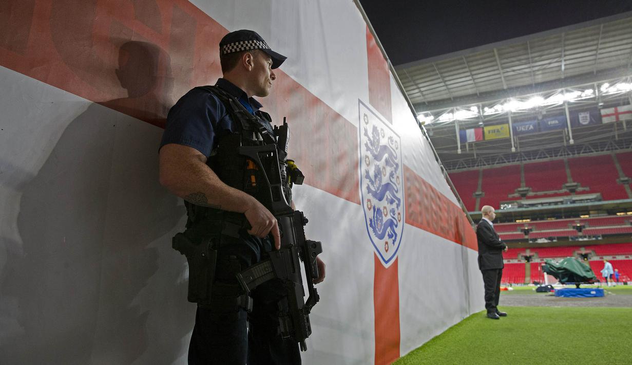 Kepolisian Inggris dengan senjata lengkap menjaga latihan timnas Prancis jelang laga ujicoba melawan Inggris di Stadion Wembley, Inggris, Senin (16/11/2015). (AFP Photo/Adrian Dennis)