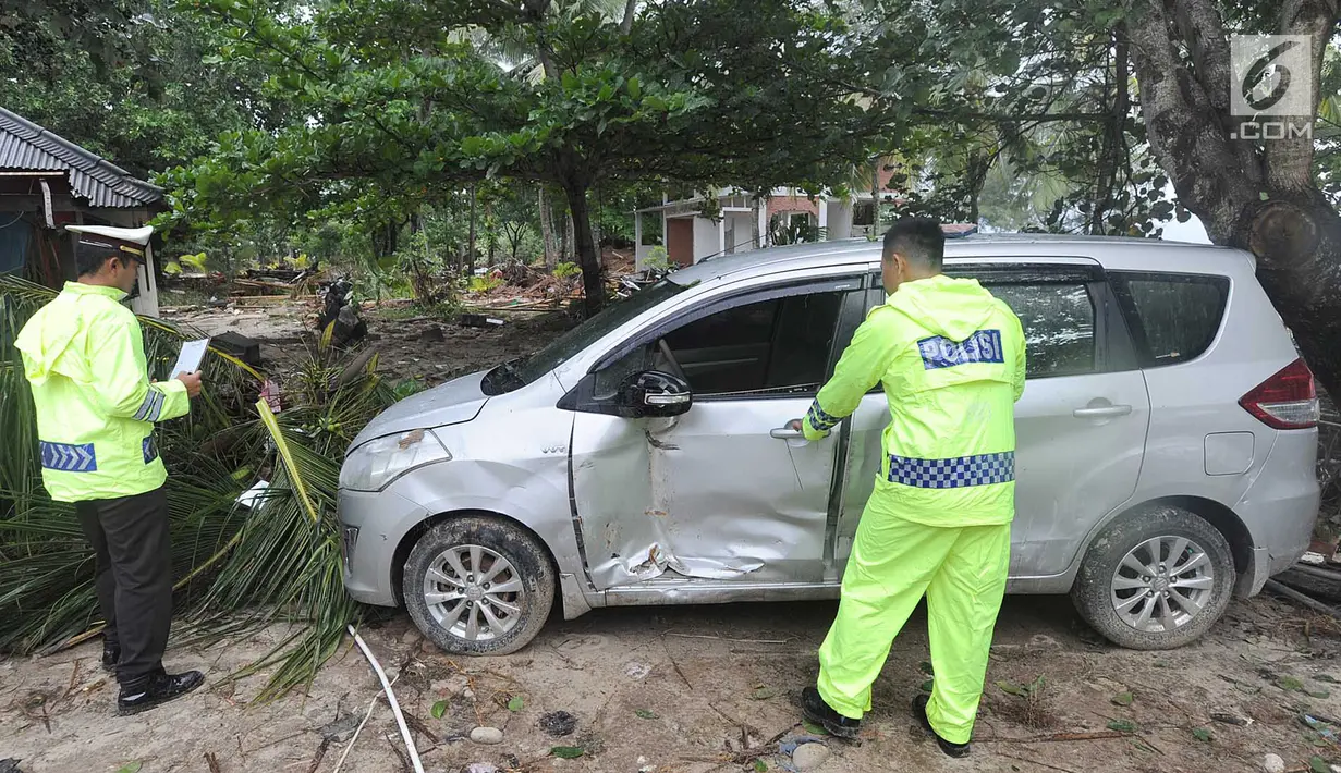 Petugas melakukan identifikasi mobil yang rusak akibat terjangan tsunami di Tanjung Lesung Beach Club, Pandeglang, Banten, selasa (25/12). Indentifikasi dilakukan untuk mencocokan kepemilikan kendaraan dengan para korban tsunami. (Merdeka.com/Arie Basuki)