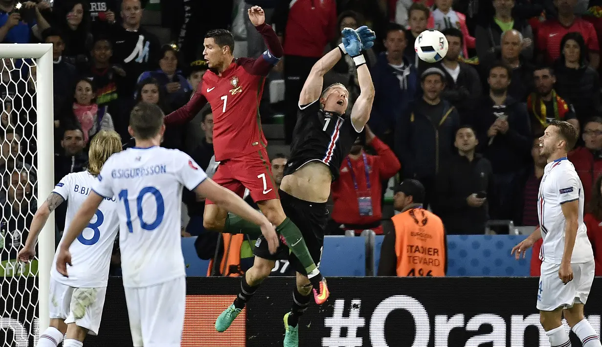 Kiper Islandia, Hannes Halldersson, menepis sundulan bintang Portugal, Cristiano Ronaldo, pada laga Grup F Piala Eropa di Stadion Geoffroy Guichard, St Etienne, Rabu (14/6/2016). Islandia bermain imbang 1-1 dengan Portugal. (AFP/Jeff Pachoud)