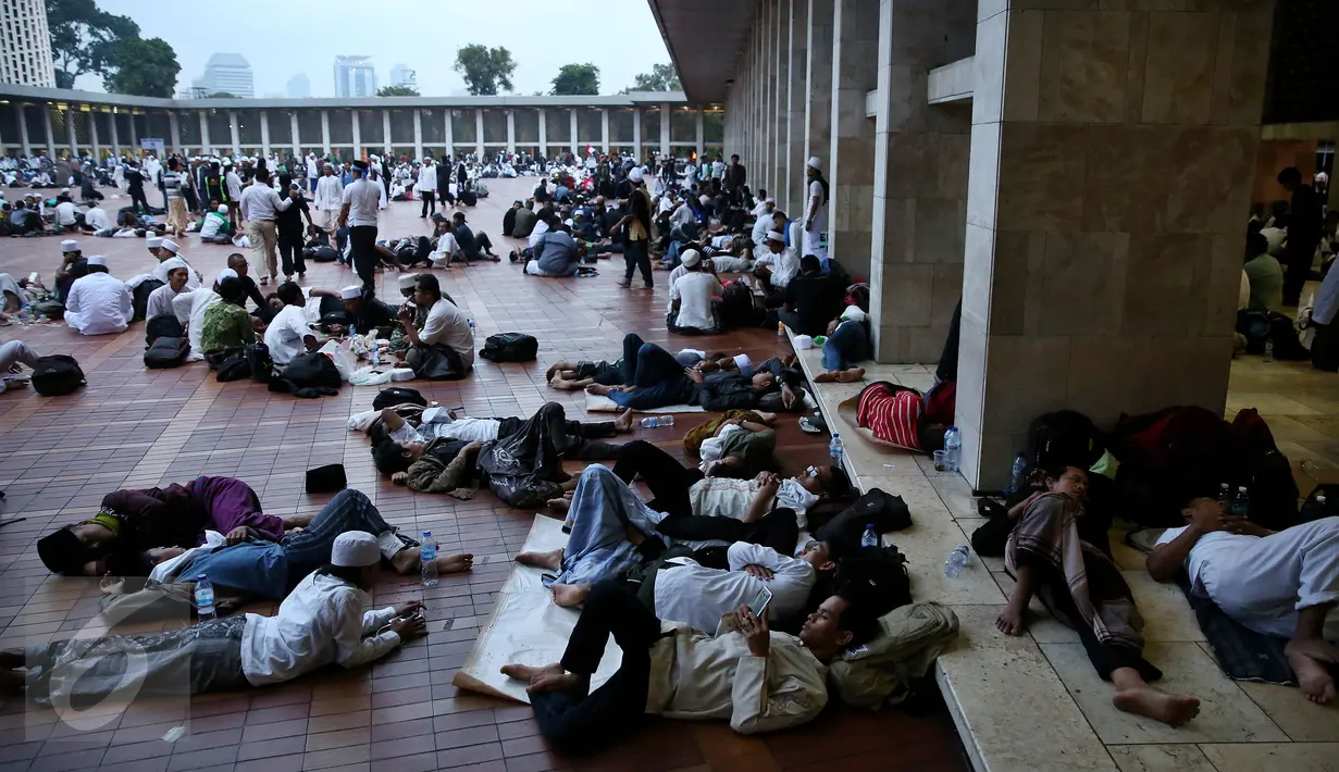 Ribuan umat muslim dari berbagai daerah sedang beristirahat usai melakukan perjalanan dan menjalankan salat Shubuh di Masjid Istiqlal, Jakarta. (04/10). Lebih dari 70 bus berukuran besar berjejer di kompleks Masjid Istiqlal. (Liputan6.com/Johan Tallo)
