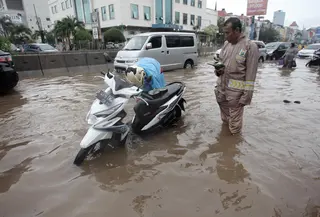 Seorang pengendara memperbaiki motornya yang mogok saat melintasi banjir di Jalan Boulevard Barat Raya, Kelapa Gading, Jakarta, Kamis (15/2). Hujan lebat yang mengguyur Jakarta mengakibatkan sejumlah wilayah terendam banjir. (Liputan6.com/Arya Manggala)