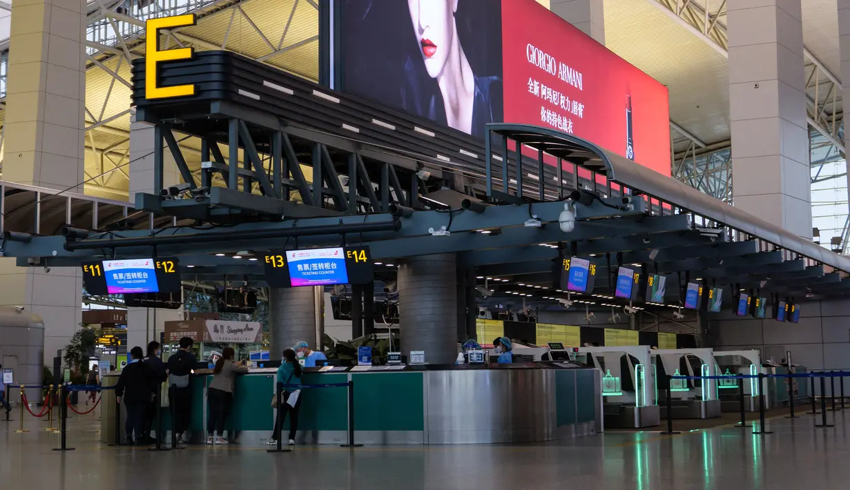Penumpang berbaris di konter check-in China Eastern di Bandara Internasional Baiyun, Guangzhou, selatan China, Senin (21/3/2022). Pesawat Boeing 737 milik China Eastern Airlines yang membawa yang terdiri dari 123 penumpang dan sembilan awak kabin, jatuh di kawasan lereng gunung. (STR/AFP)