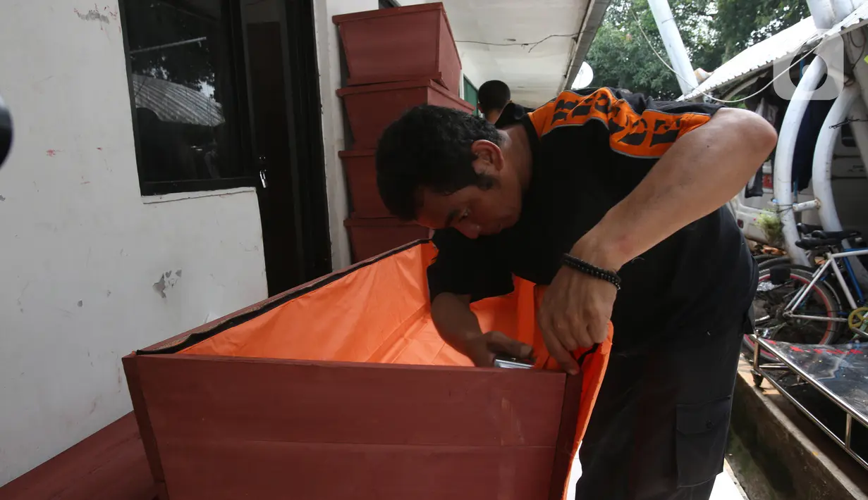 Petugas menyelesaikan pembuatan peti mati khusus jenazah virus corona atau Covid-19 di Dinas Pertamanan dan Pemakaman Jakarta, Sabtu (28/3/2020). Peti mati korban meninggal akibat corona Covid-19 itu dilapisi kantong jenazah dan kain kafan untuk mencegah penyebaran virus. (Liputan6.com/Angga Yuniar)