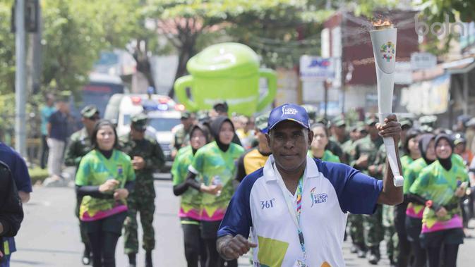 Legenda Taekwondo, Abdul Rojak, membawa Obor Asian Games mengelilingi kota Banjarmasin, Kalimantan Selatan, Senin (30/7/2018). (Bola.com/Reza Bachtiar)