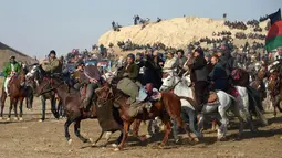 Penunggang kuda Afghanistan memperebutkan bangkai saat pertandingan olahraga tradisional Buzkashi di Mazar-i-Sharif, Afghanistan (20/12). Mereka merebutkan bangkai seekor binatang ternak yang dibawa di sekitar penanda atau bendera. (AFP/Farshad Usyan)