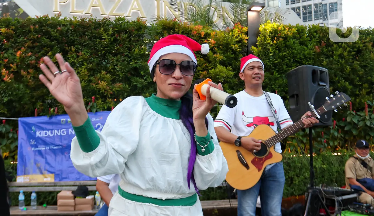 Musisi mengelar pertunjukan musik bernuansa Natal di jalur Pedestrian Bundaran HI, Jakarta Pusat, Selasa (20/12/2022). Pergelaran musik bernuansa Natal tersebut sebagai bentuk pertunjukan untuk menghibur warga yang melintas di Kawasan itu. (Liputan6.com/Angga Yuniar)