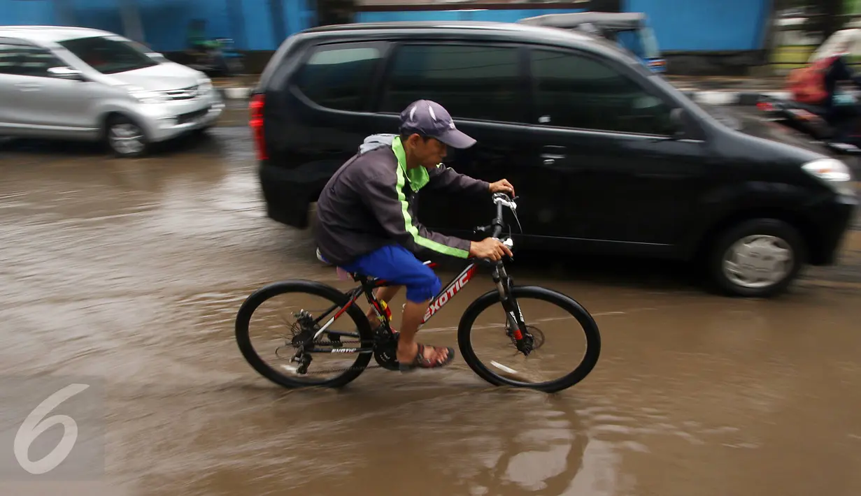 Seorang warga menggunakan sepedanya mencoba menerobos genangan air di Jalan Cikini Raya, Jakarta, Sabtu (7/11). Meski baru pertama kali diguyur hujan selama musim kemarau, jalan tersebut langsung terendam air. (Liputan6.com/ Immanuel Antonius)