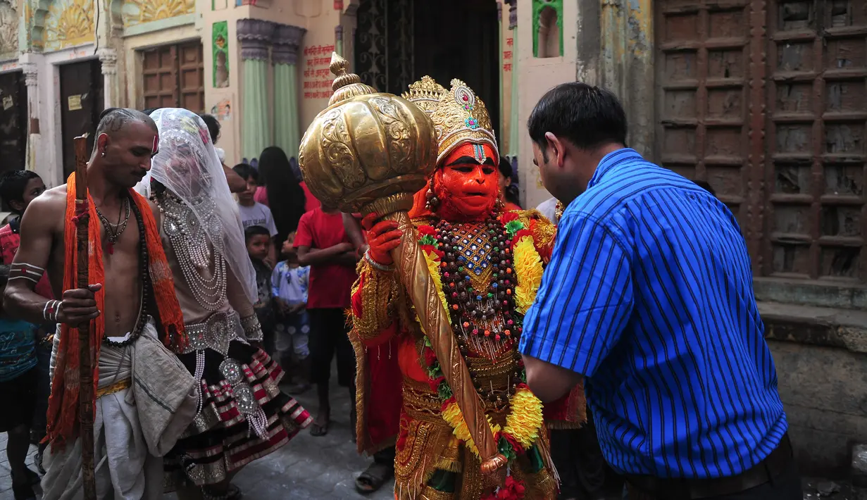 Seorang pria berpakaian seperti dewa Hanoman memberkati warga setempat saat festival Jayanti di Allahabad, India (18/10). Di India, hanoman dipuja sebagai dewa pelindung dan beberapa kuil didedikasikan untuk memuja dirinya. (AFP Photo/Sanjay Kanojia)