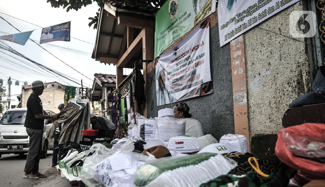 Pedagang menggelar lapak di depan poster penyambutan Habib Rizieq di Jalan Petamburan III, Tanah Abang, Jakarta, Senin (9/11/2020). Sejumlah pedagang yang menjual beragam atribut FPI pun terlihat berjejer di sepanjang jalan. (merdeka.com/Iqbal S. Nugroho)