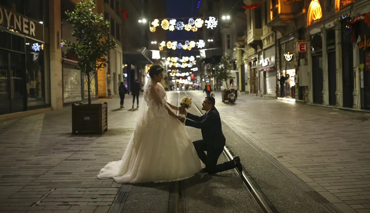 Yasemin Tuna dan Murat Targut yang baru menikah melakukan pemotretan di Istiklal Street yang sepi di Istanbul, Turki, Kamis (29/4/2021.Warga menimbun bahan makanan, pembeli memenuhi pasar, dan banyak warga meninggalkan kota karena lockdown COVID-19 paling ketat mulai berlaku. (AP Photo/Emrah Gurel)