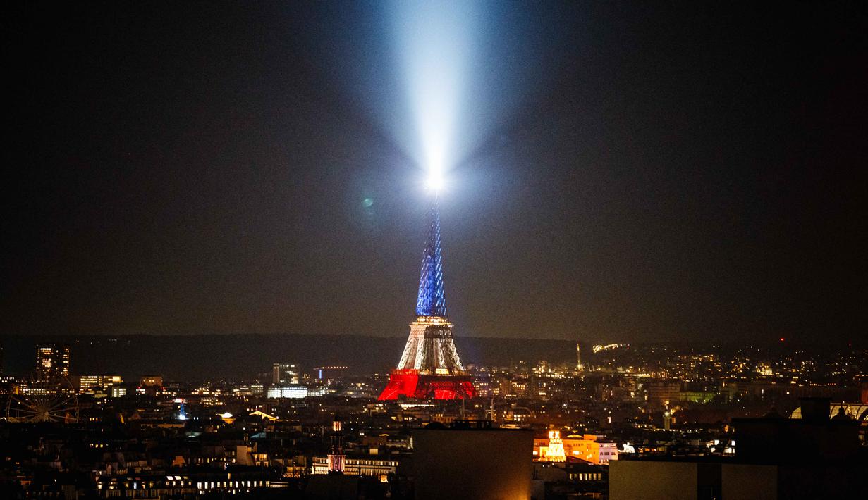 Foto ini menunjukkan Menara Eiffel yang diterangi dengan warna bendera nasional Prancis saat peringatan ke-10 serangan teroris Paris yang terjadi pada 2015, di Paris, pada 12 November 2025. Prancis memperingati satu dekade tragedi berdarah pada 13 November 2015. (Dimitar DILKOFF/AFP)