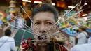 Seorang pemuja dari Kuil Samkong menusukkan benda tajam ke pipi saat memeriahkan festival vegetarian di Phuket, Thailand (17/10/2015). Festival ini menampilkan aksi ekstrem pemuja dengan menusukkan benda tajam ke wajah. (REUTERS/Jorge Silva)