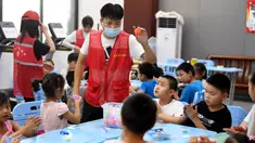 Sukarelawan bermain bersama anak-anak di tempat pengungsian sementara Sekolah Menengah No.168, Hefei, Provinsi Anhui, China, Rabu (29/7/2020). Lebih dari 300 penduduk desa di Kota Sanhe, Hefei, dievakuasi ke sekolah itu akibat terdampak banjir. (Xinhua/Liu Junxi)