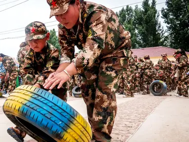 Sejumlah anak-anak mendorong ban saat mensimulasikan latihan militer di sebuah taman kanak-kanak di provinsi Henan, China (30/5). Latihan militer ini dilakukan untuk menjelang Hari Anak Internasional yang jatuh pada 1 Juni. (AFP)