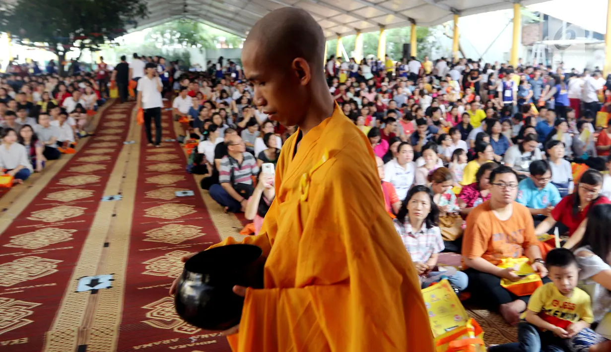 Seorang biksu berjalan di depan umat Buddha yang merayakan Hari Raya Waisak 2562 BE/2018 di Wihara Ekayana Arama, Jakarta Barat, Selasa (29/5). Puja Bakti Massal Waisak 2562 BE diikuti oleh ribuan umat Buddha. (Liputan6.com/JohanTallo)