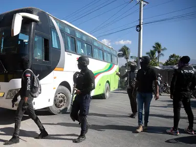 Petugas polisi bersenjata dan bertopeng memaksa seorang pengemudi memarkir busnya untuk digunakan sebagai barikade saat protes untuk mengecam tata kelola polisi yang buruk di Port-au-Prince, Haiti, 26 Januari 2023. Sekelompok polisi Haiti melakukan protes terhadap pemerintah yang dinilai tidak mengambil tindakan tegas atas kematian 14 polisi oleh geng kriminal. (AP Photo/Odelyn Joseph)