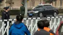 Polisi dan petugas keamanan berjaga ketika iring-iringan mobil berjalan di sepanjang jalan dekat Wisma Negara Diaoyutai, Beijing, Selasa (27/3). Kabar yang berkembang menyebut Pemimpin Korea Utara Kim Jong-un tiba di Beijing. (AP Photo/Mark Schiefelbein)